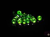 a pile of green crystals sitting on top of a black surface