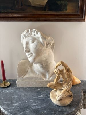 a statue of a man sitting on a table next to a candle