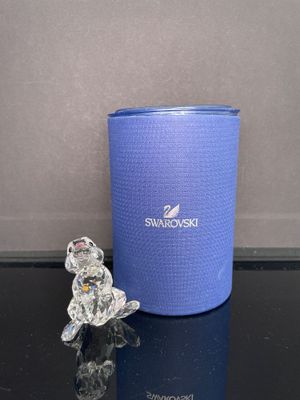 un petit ours en verre posé à côté d'un récipient bleu