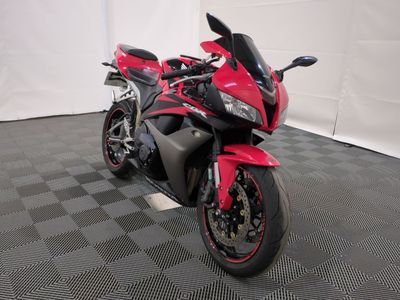 une moto rouge et noire garée sur un sol à damier noir et blanc