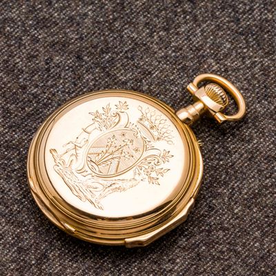 une montre de poche en or posée sur un tissu noir