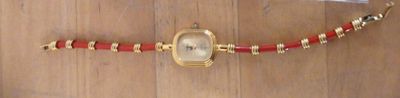 a picture of a wrist watch with a red and gold band