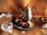 a silver plate with a silver tea pot and a silver tray with chocolates on it