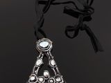 a silver necklace with a triangle shaped pendant on a black background