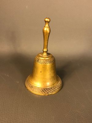 antique brass bell with a man on top of it sitting on a table