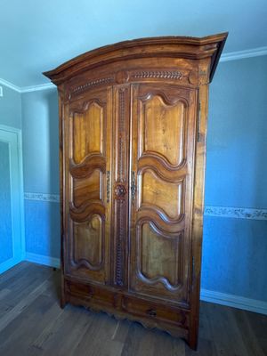 a wooden armoire in the corner of a room