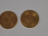 two gold coins sitting on a white surface