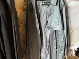 two coats hanging on a clothes rack next to a bed