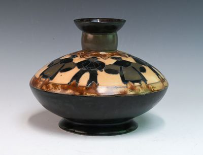 a black and brown vase sitting on a white surface