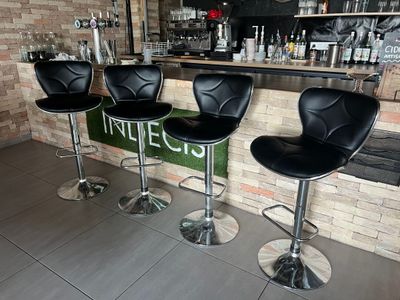 trois tabourets de bar en cuir noir sont disposés devant un mur de briques