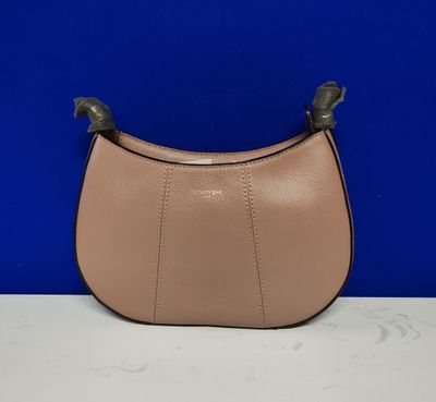 un sac à main en cuir rose muni d'une poignée en métal, posé sur une table blanche
