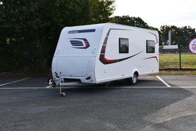 une petite caravane blanche garée sur un parking