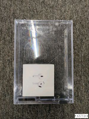 Une pomme et des AirPods se trouvent dans une boîte transparente posée sur un tapis