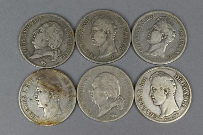 six different types of silver coins are shown on a gray surface