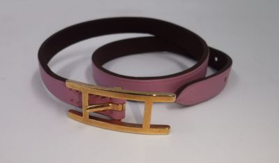 ceinture en cuir rose et noir avec une boucle dorée sur un fond blanc
