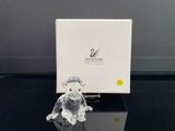 figurine en cristal représentant un ours en peluche assis devant une boîte blanche