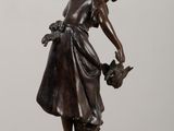 bronze statue of a woman watering a plant on a table