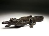une statue représentant un petit alligator posée sur une surface blanche