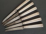 six knives are lined up in a row on a black surface