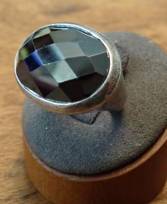 a silver ring with a faceted black stone on it