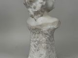 white marble bust of a woman on a pedestal on a gray background