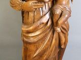 statue en bois représentant une femme tenant un enfant dans ses bras, posée sur un socle