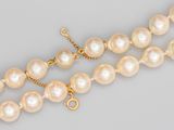 un gros plan sur un collier de perles muni d'un fermoir en or