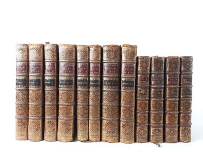 several old books lined up in a row on a white surface