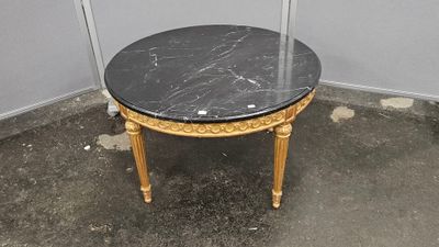 une petite table avec un plateau en marbre noir et des pieds dorés