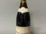 bottle of red wine with a red cap sitting on a white surface