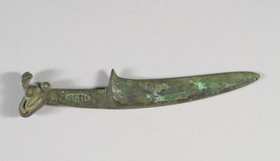 une image représentant un couteau en bronze posé sur une surface blanche