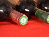 several bottles of wine are lined up on a red cloth
