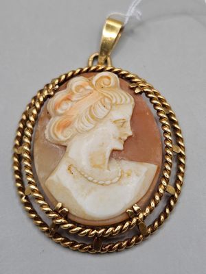 a gold and shell cameo pendant with a woman ' s face
