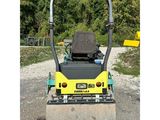 a close up of a road roller on gravel with trees in the background