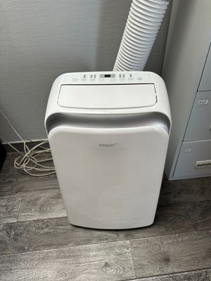 an air conditioner sitting on a wooden floor next to a wall