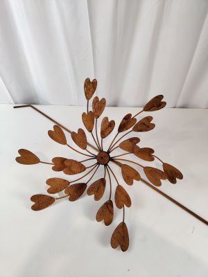 un gros plan d'une sculpture métallique représentant des feuilles sur une surface blanche
