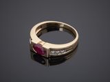 a gold ring with a ruby stone and diamonds on a black surface