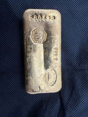 un lingot d'argent portant un poinçon, posé sur un tissu bleu
