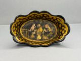 an old black and gold plate with a painting of a man and woman