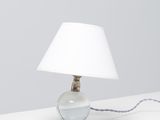 une lampe de table surmontée d'un abat-jour blanc, posée sur une surface blanche