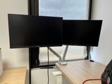 deux écrans posés sur un bureau devant une fenêtre