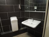a bathroom with a sink, mirror and toilet paper dispenser