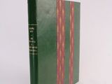 an old book with a green cover sitting on a white surface