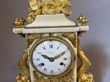 a white clock with a gold decoration on it