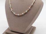 un collier en or et en argent orné de perles, porté par un mannequin