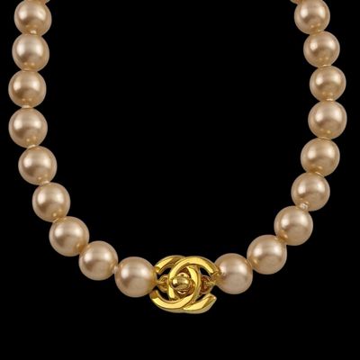 un gros plan sur un collier de perles muni d'un fermoir en or