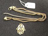 un gros plan d'un collier en or orné d'une main de Hamsa