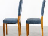 pair of blue velvet chairs with wooden legs in the shape of a chair
