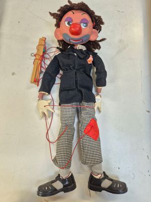 une poupée avec un nez rouge, une veste noire et un pantalon noir