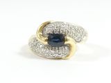 a close up of a blue sapphire and diamond ring on a white surface